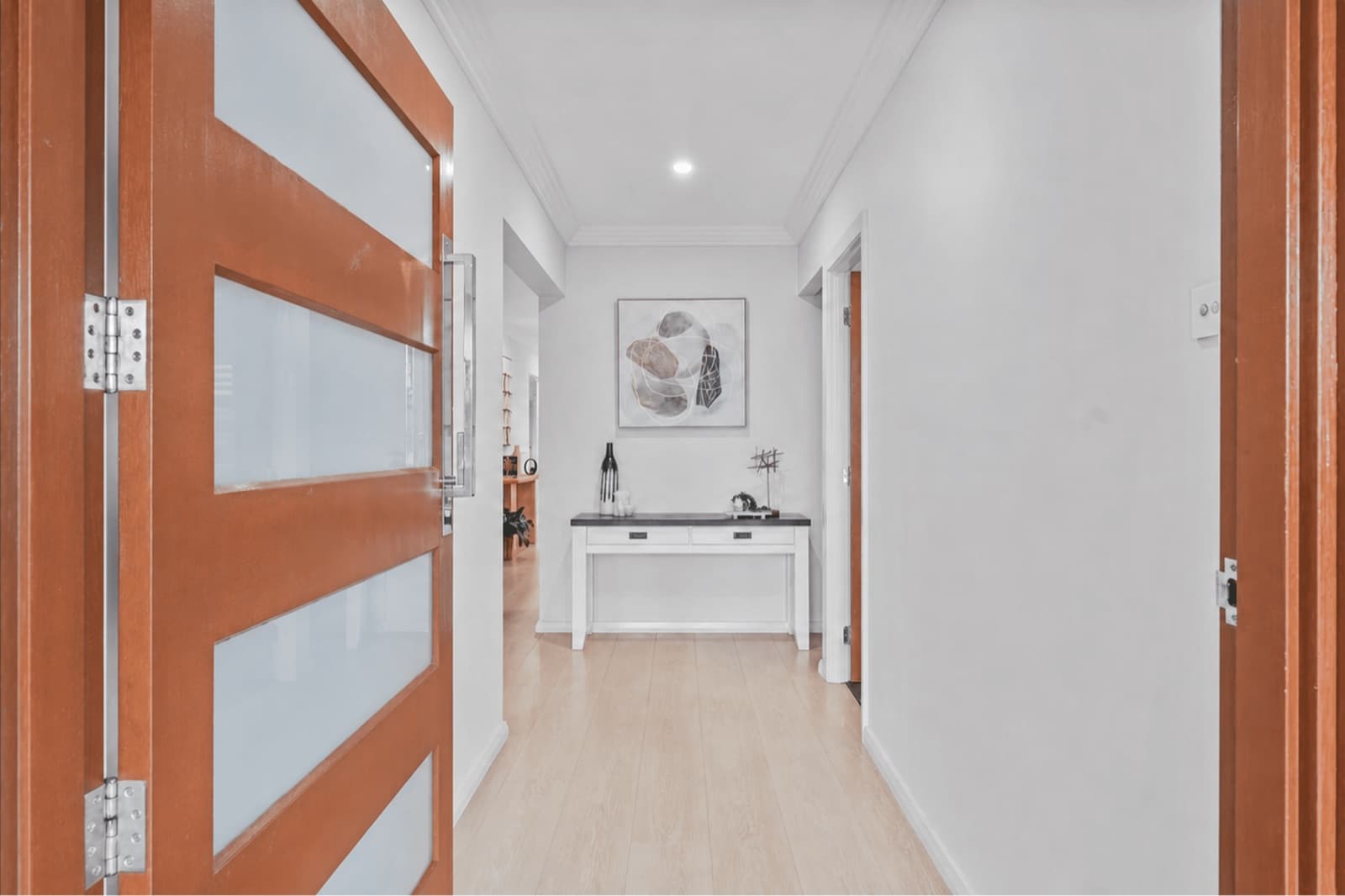 Wide entry hallway with timber front door and console table