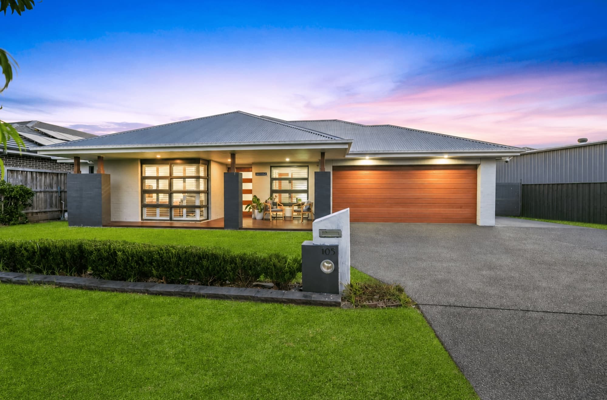 Street view of the Chisholm SIL home at dusk — modern single-level house with landscaped lawn and wide driveway