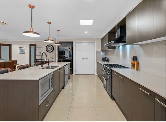 Open galley kitchen with long island bench, wall oven and walk-in pantry