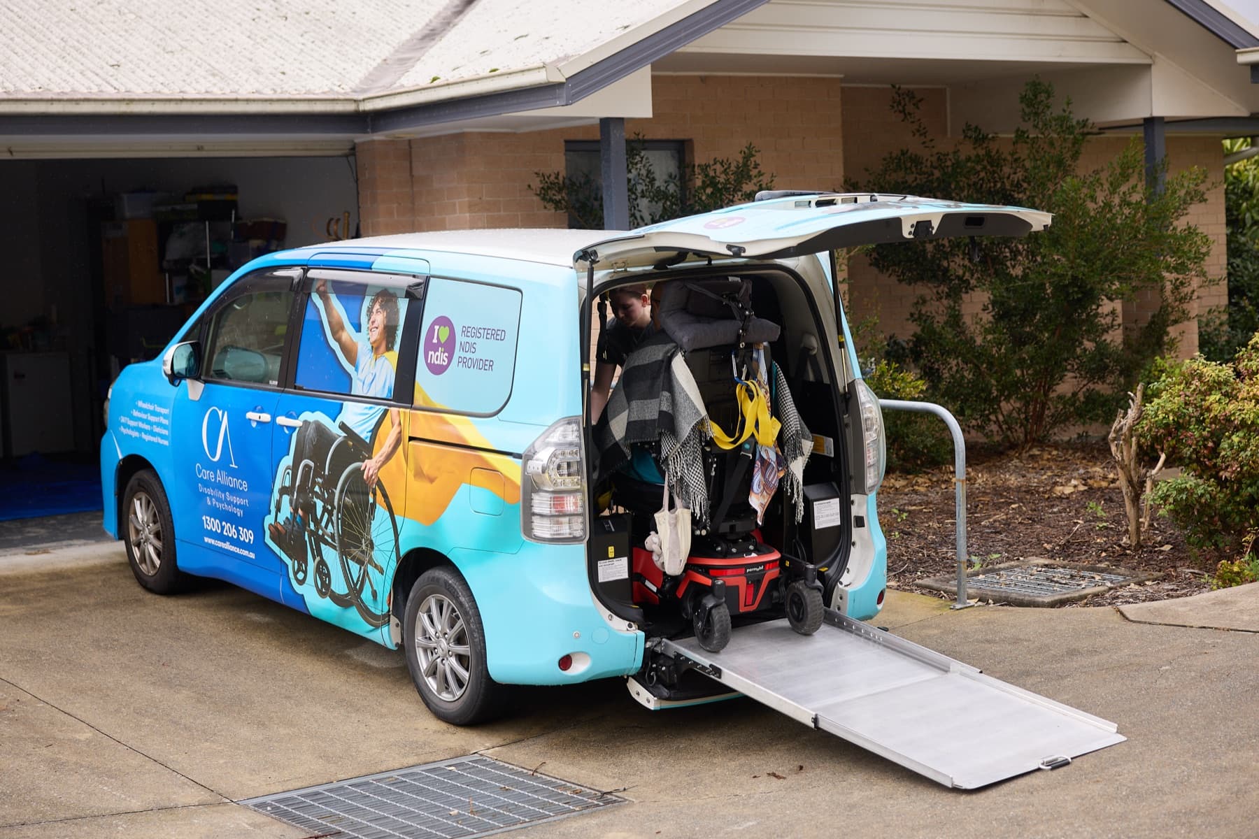 A Care Alliance wheelchair-accessible van with its rear ramp lowered